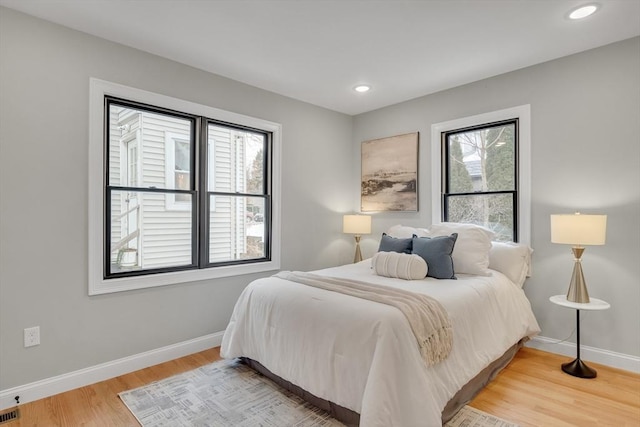 bedroom with multiple windows and hardwood / wood-style floors