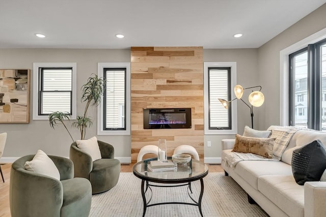 living room featuring light hardwood / wood-style floors, a large fireplace, and wooden walls