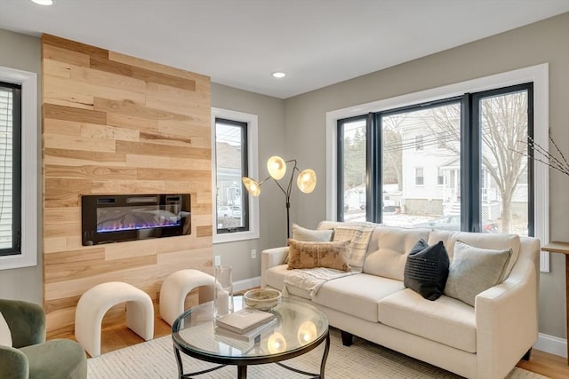 living room with hardwood / wood-style flooring, wooden walls, plenty of natural light, and a fireplace