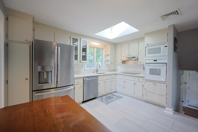 61 Colwell, Dedham, MA 02026 - kitchen featuring stainless steel appliances, a skylight, under cabinet range hood, glass insert cabinets, and light countertops