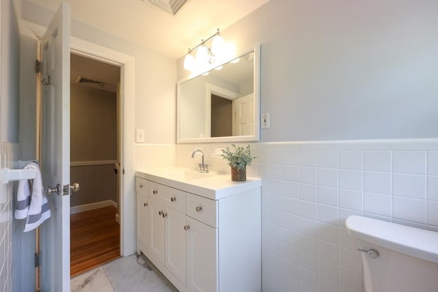 61 Colwell, Dedham, MA 02026 - bathroom with vanity, marble finish flooring, a wainscoted wall, and tile walls