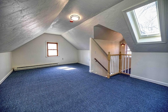 additional living space with a textured ceiling, vaulted ceiling with skylight, carpet flooring, baseboards, and baseboard heating