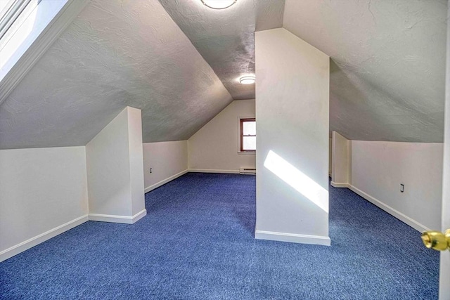 additional living space with baseboards, a textured ceiling, vaulted ceiling, and carpet