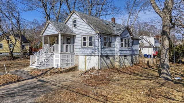 view of front facade with stairway, a porch, and a chimney