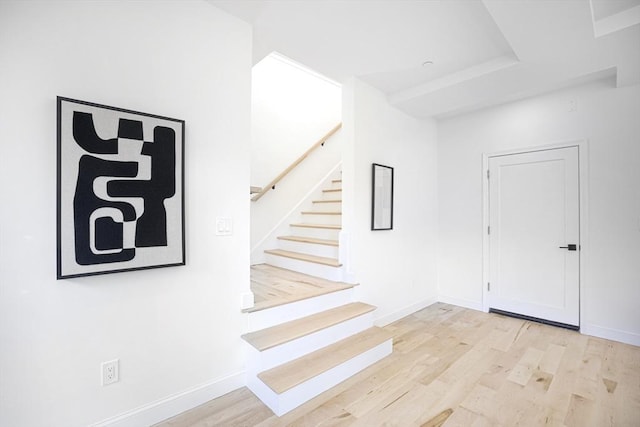 foyer entrance with light wood-style floors, stairs, and baseboards