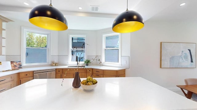 kitchen with stainless steel dishwasher, a sink, light countertops, brown cabinets, and recessed lighting