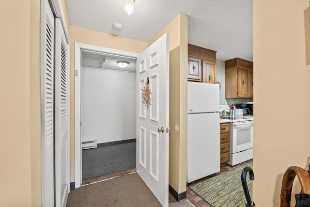 kitchen with dark carpet, white appliances, and a baseboard radiator