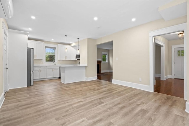 129 S Main St, Raynham, MA 02767 - unfurnished living room with a wall unit AC, light wood-type flooring, recessed lighting, baseboards, and a sink