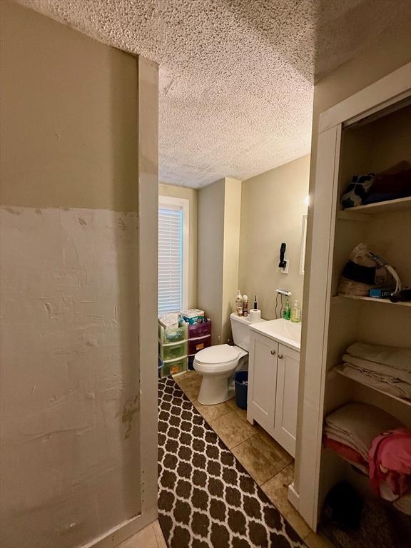 bathroom featuring toilet, vanity, a textured ceiling, and tile patterned floors