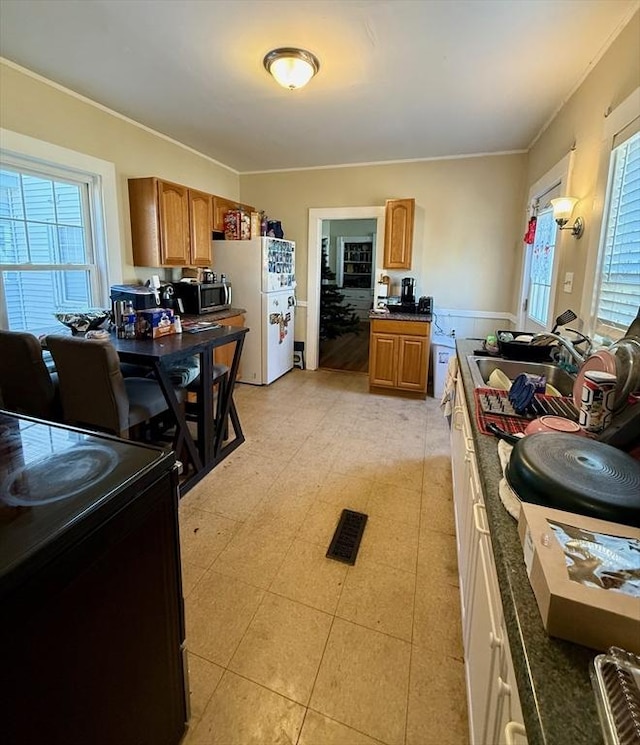 kitchen with black / electric stove, crown molding, sink, and white refrigerator