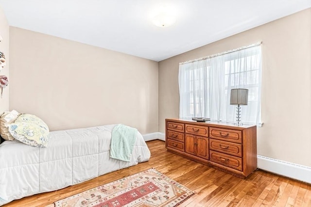 bedroom featuring a baseboard heating unit and light hardwood / wood-style floors