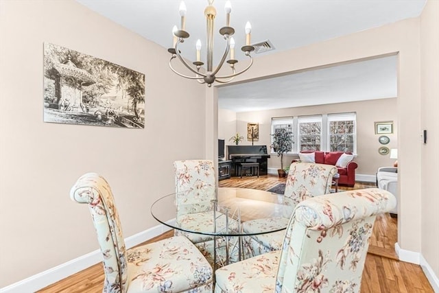 dining area with light wood-type flooring and a notable chandelier