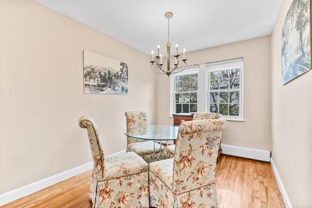 dining room featuring wood-type flooring, baseboard heating, and a notable chandelier