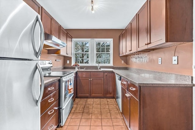 kitchen featuring sink, track lighting, light tile patterned floors, and appliances with stainless steel finishes