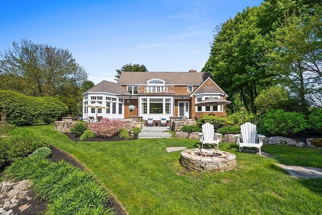 rear view of property with a yard, a balcony, a patio, and a fire pit