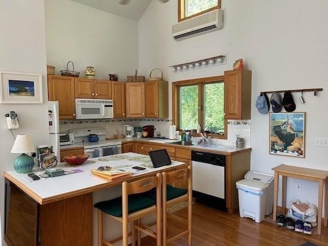 190 Longview Rd, West Tisbury, MA 02575 - kitchen with white appliances, an AC wall unit, light countertops, backsplash, and high vaulted ceiling
