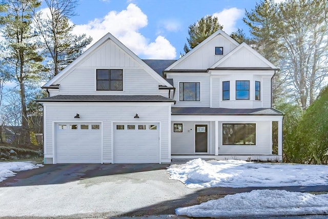 modern farmhouse with aphalt driveway, roof with shingles, a porch, board and batten siding, and a garage