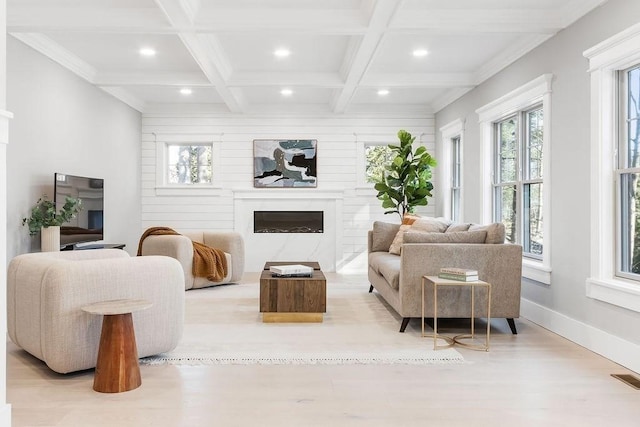 living area with beam ceiling, light wood-style flooring, a premium fireplace, coffered ceiling, and baseboards