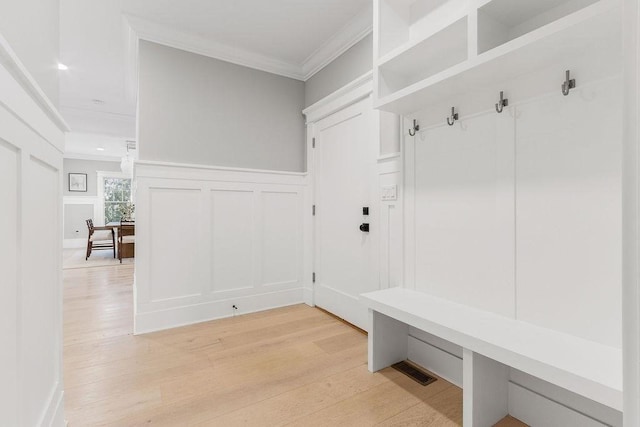 mudroom featuring ornamental molding, wainscoting, light wood-style flooring, and a decorative wall