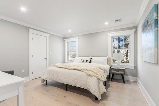 bedroom with ornamental molding, light wood-type flooring, visible vents, and baseboards