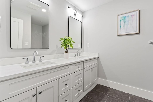 full bath featuring double vanity, a sink, baseboards, and tile patterned floors