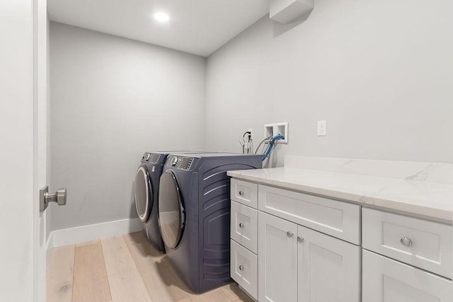 laundry area with baseboards, cabinet space, light wood-style flooring, and washer and dryer