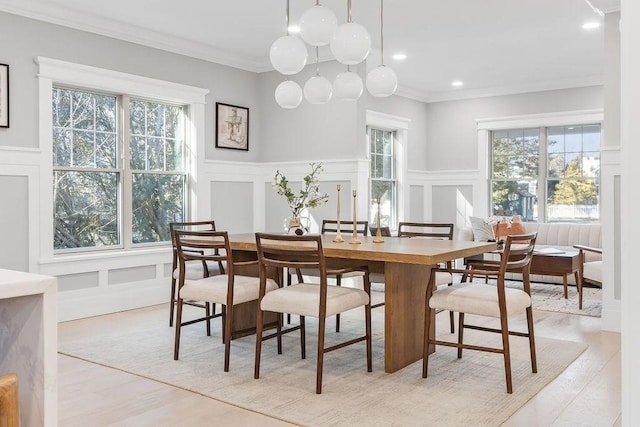 dining room featuring crown molding, recessed lighting, light wood-style flooring, and a decorative wall