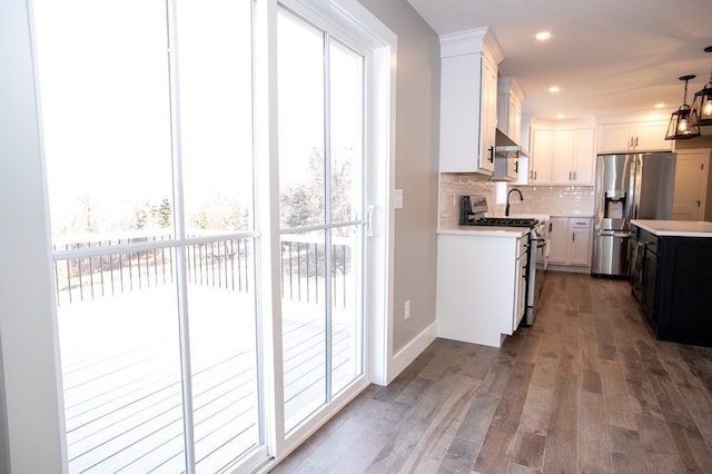 kitchen featuring pendant lighting, white range with gas stovetop, tasteful backsplash, white cabinetry, and stainless steel fridge with ice dispenser