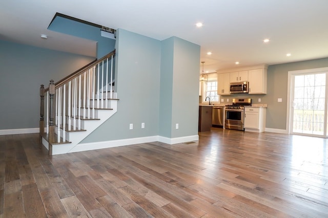 unfurnished living room featuring wood-type flooring and sink