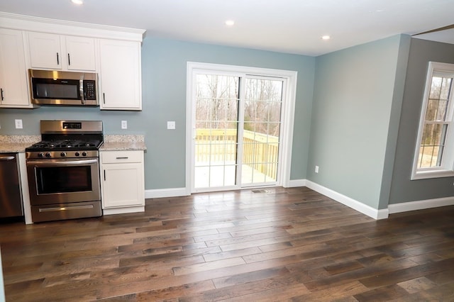 kitchen with dark hardwood / wood-style floors, light stone counters, white cabinetry, and appliances with stainless steel finishes