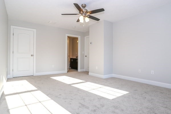 unfurnished bedroom with ceiling fan, light colored carpet, and ensuite bath