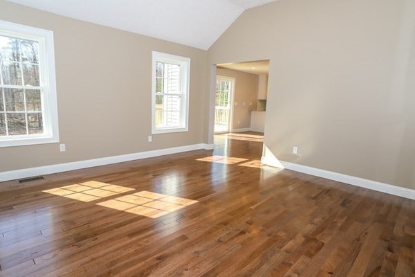 spare room with dark wood-type flooring and lofted ceiling