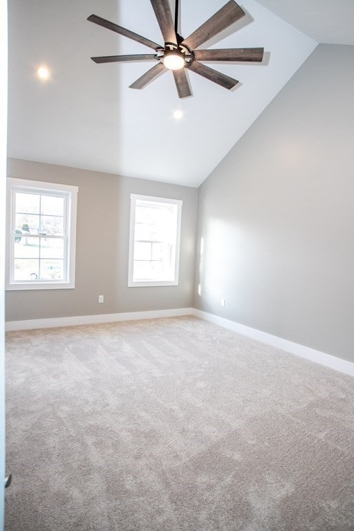 carpeted empty room with ceiling fan and high vaulted ceiling