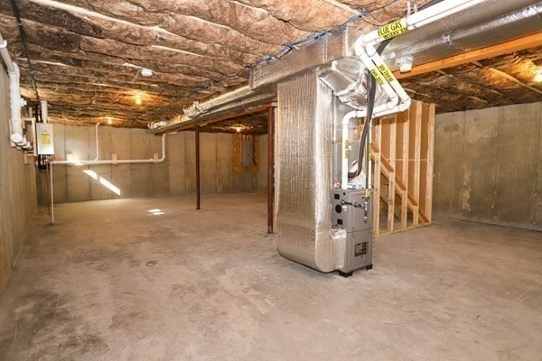 basement featuring electric panel, heating unit, and water heater