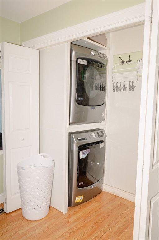 laundry room featuring wood-type flooring and stacked washer and dryer