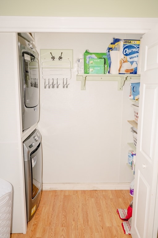 laundry room featuring hardwood / wood-style flooring and stacked washer / drying machine