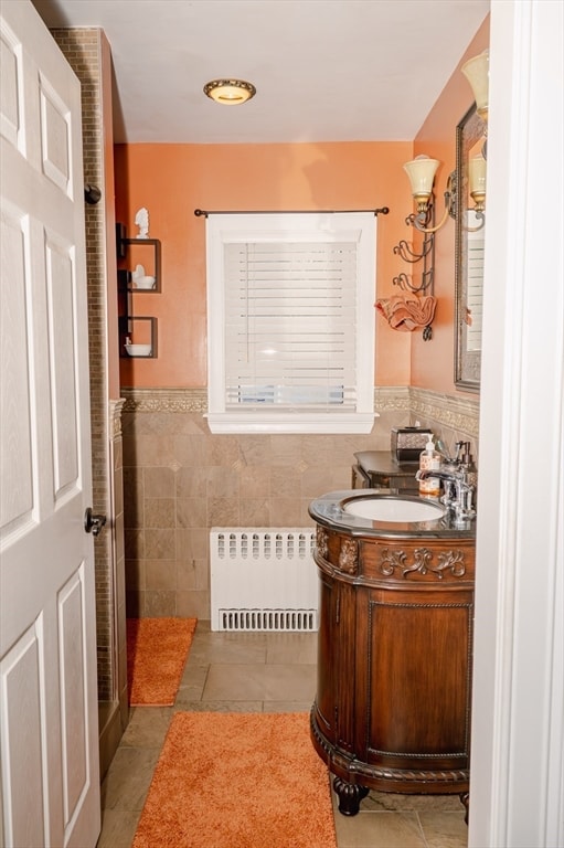 bathroom with tile patterned floors, radiator, vanity, and tile walls