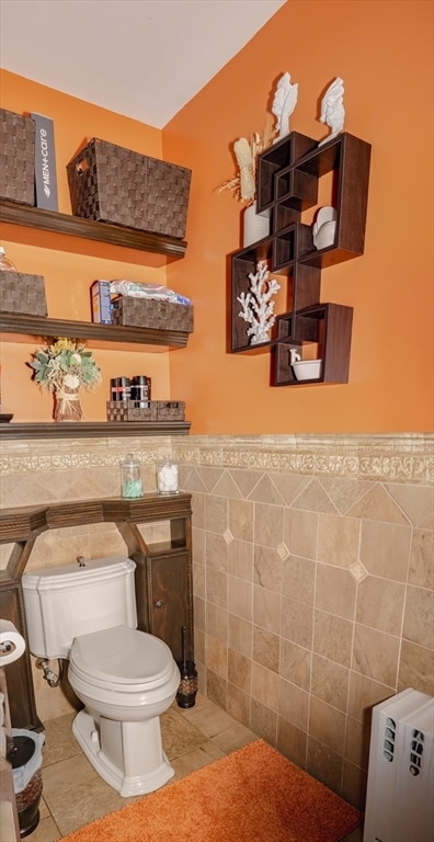 bathroom with tile patterned flooring, toilet, and tile walls