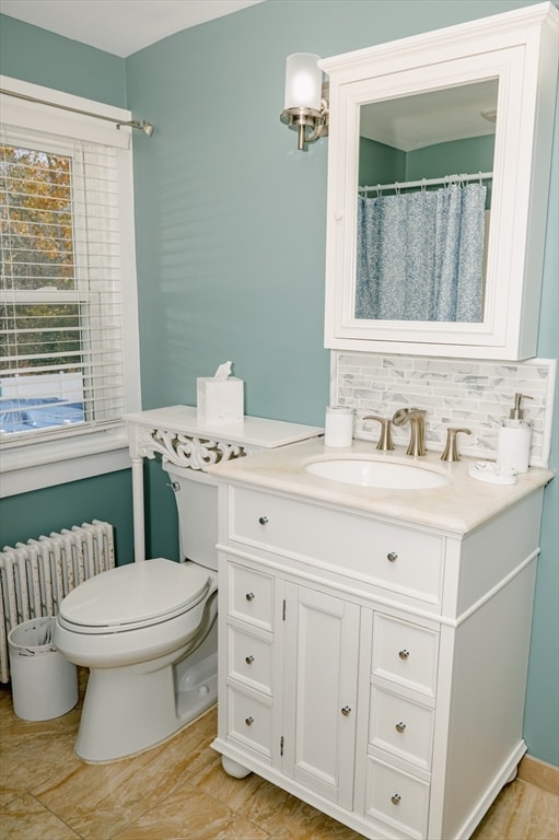 bathroom with vanity, toilet, backsplash, and radiator