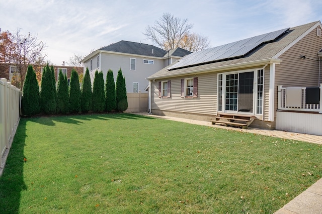 back of property featuring solar panels and a lawn