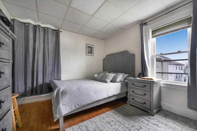 bedroom featuring a drop ceiling and wood finished floors