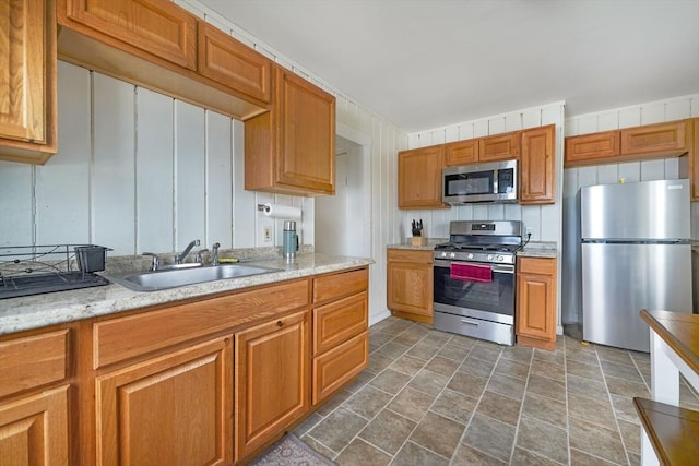 kitchen with light countertops, stone finish flooring, appliances with stainless steel finishes, and a sink
