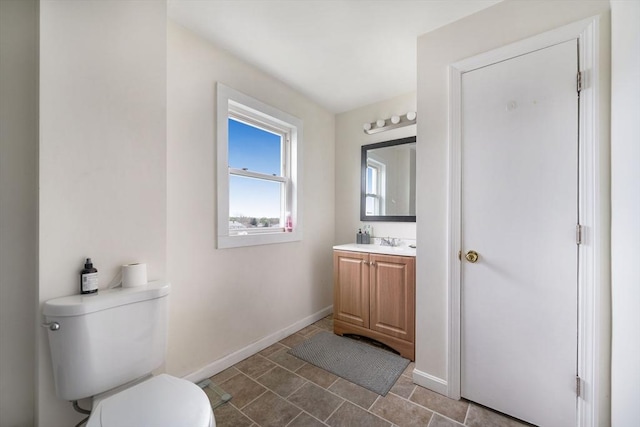 bathroom featuring toilet, baseboards, and vanity