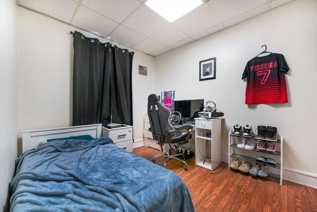 bedroom with wood finished floors and a drop ceiling