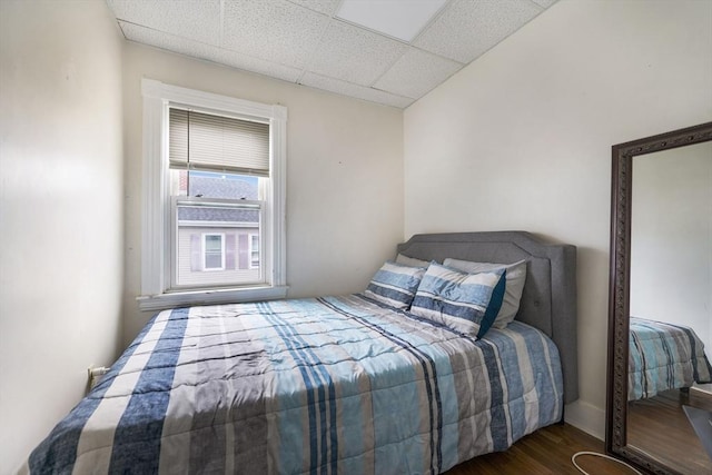 bedroom with a paneled ceiling and wood finished floors