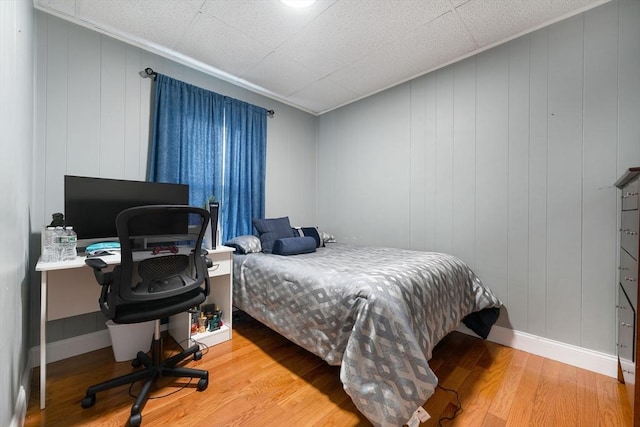 bedroom featuring crown molding, baseboards, and wood finished floors