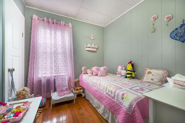 bedroom with wood-type flooring, ornamental molding, and multiple windows
