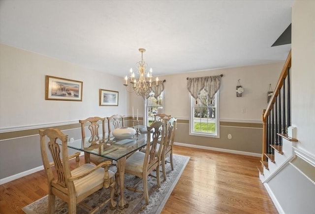 dining room featuring baseboards, an inviting chandelier, stairway, and light wood-type flooring