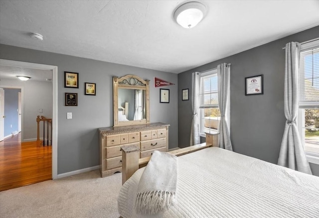 bedroom featuring baseboards, multiple windows, and light carpet
