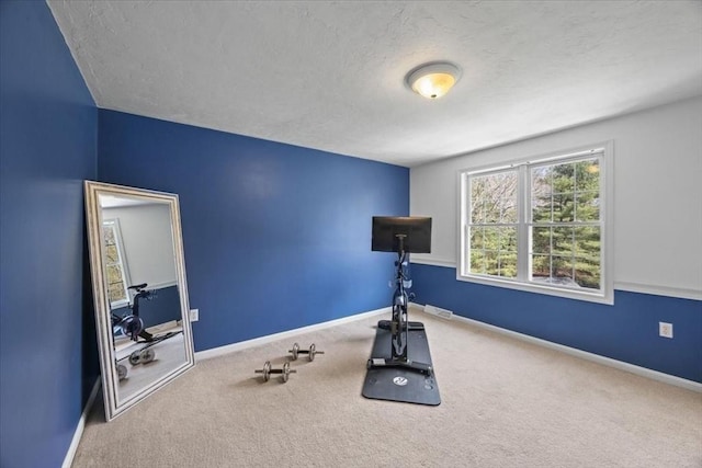 workout room featuring baseboards, carpet, and a textured ceiling